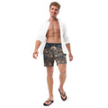 Man wearing Cymatics Sacred Geometry Recycled Swim Trunks in black and gold pattern, standing on beach