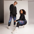 Couple wearing Galaxy Sacred Geometry Unisex Track Pants in cosmic mandala pattern, full lifestyle shot in studio