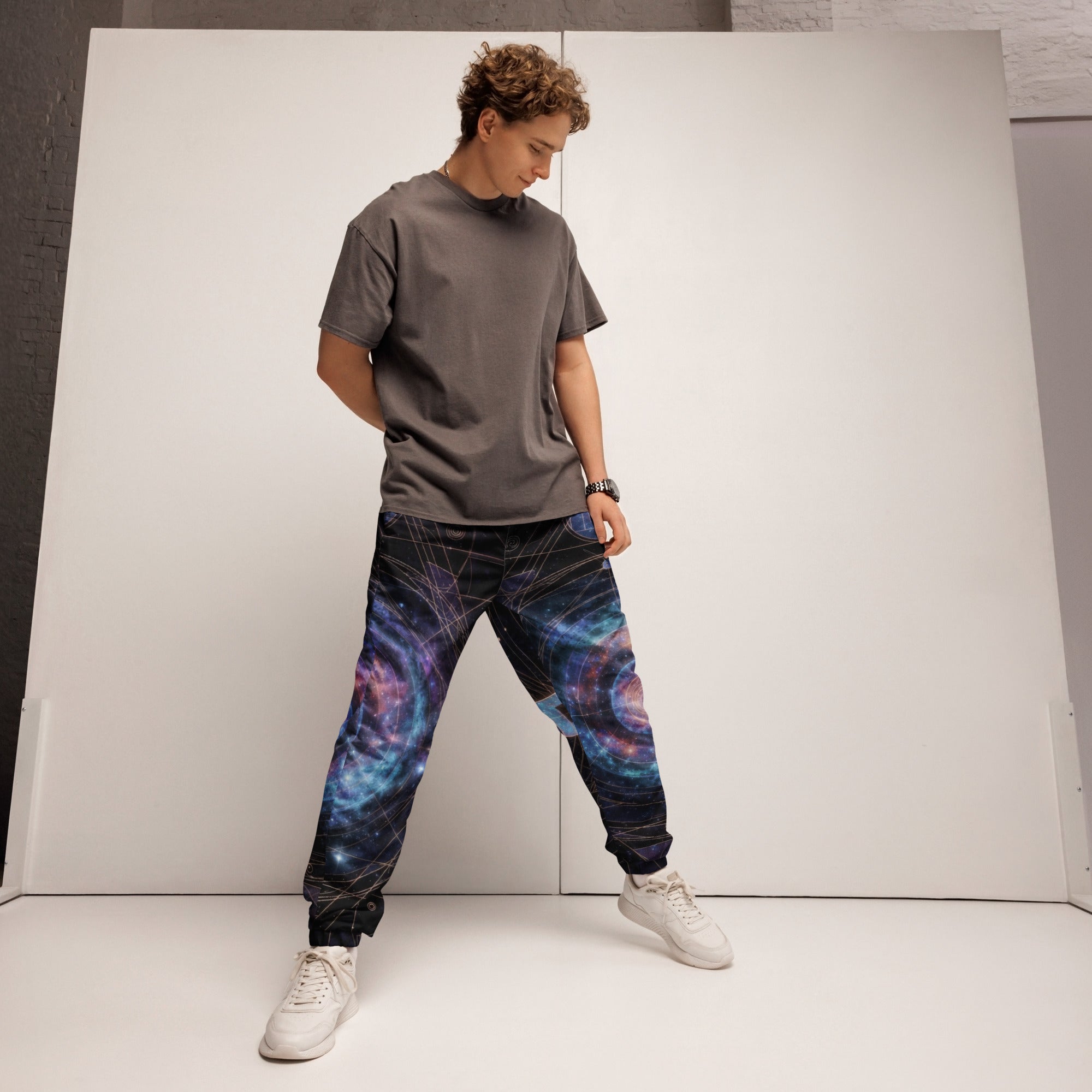 Man wearing Galaxy Sacred Geometry Track Pants in cosmic pattern, standing in studio